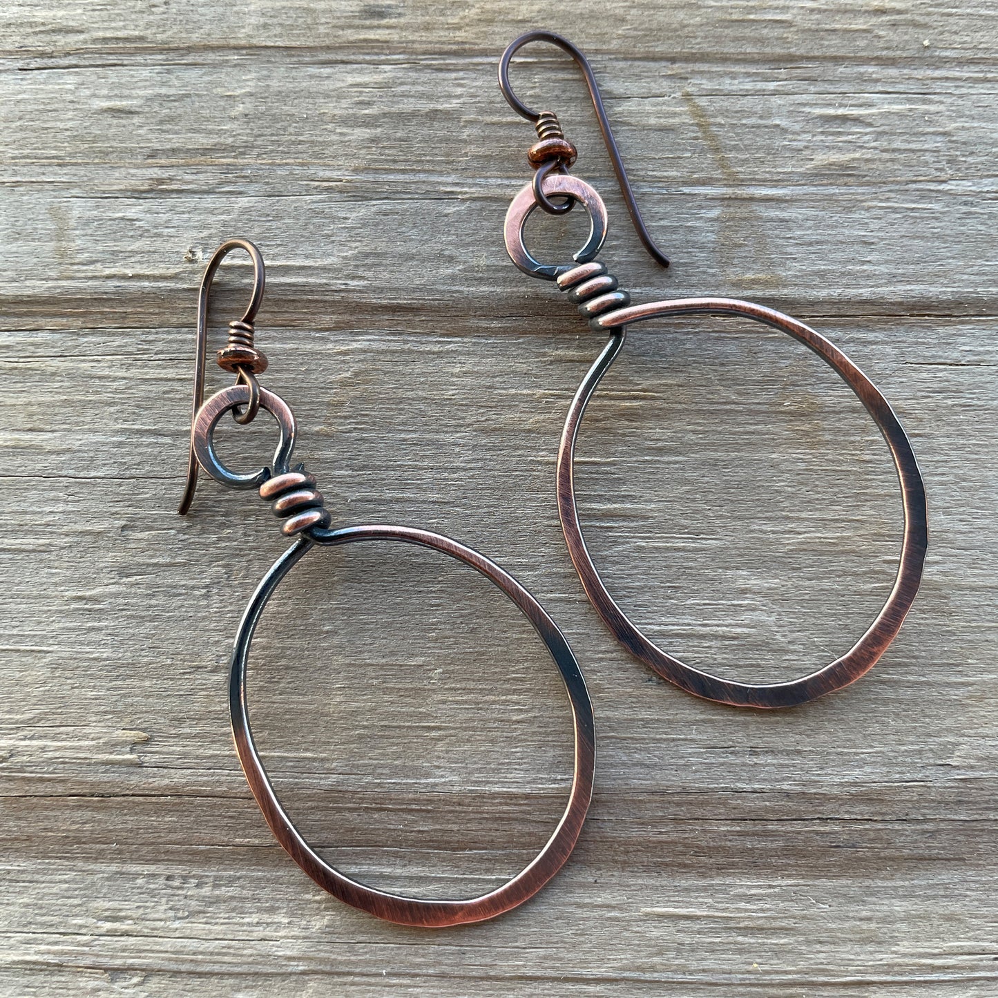 Copper hoop earrings on a wooden surface