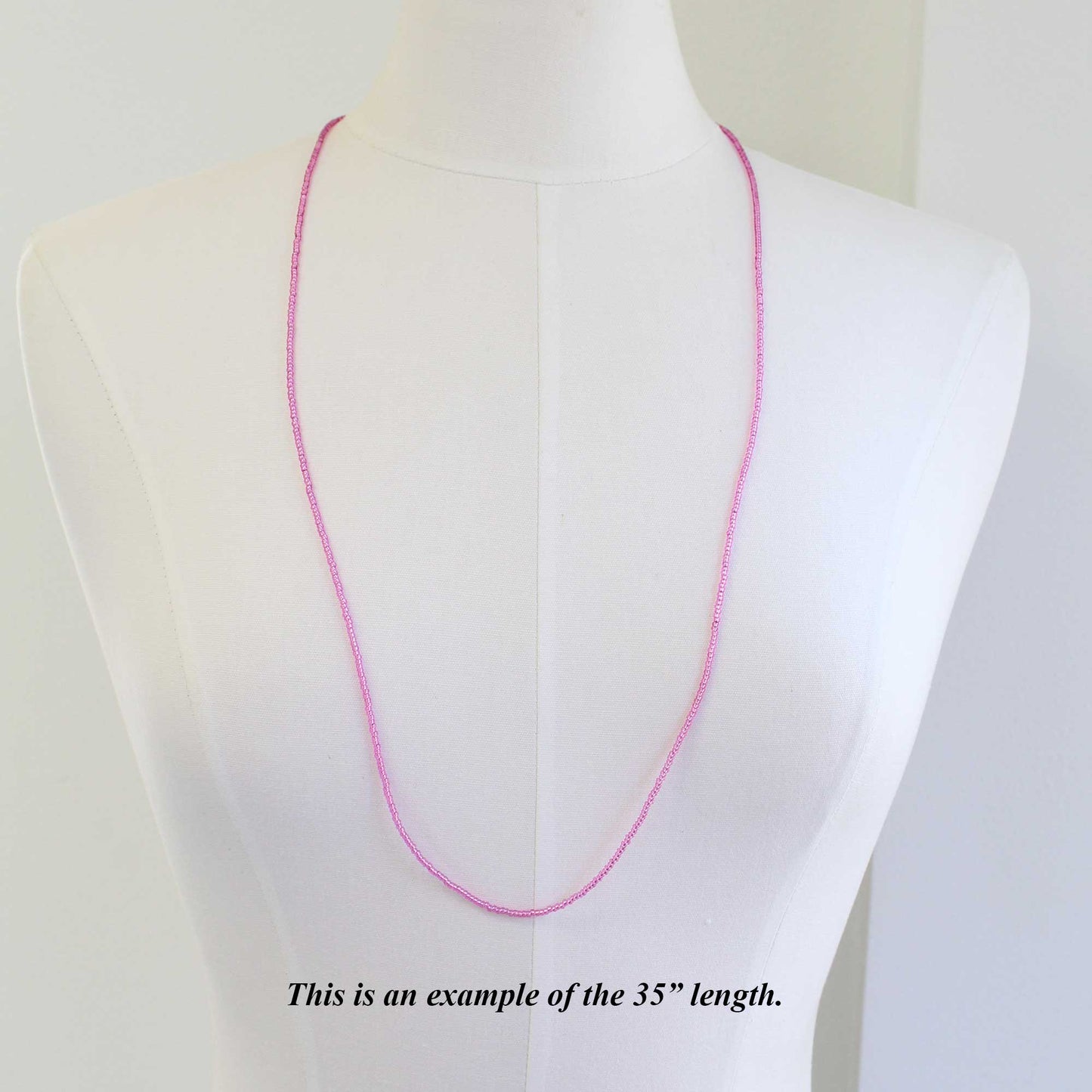 Pink necklace on a mannequin with text indicating length 35