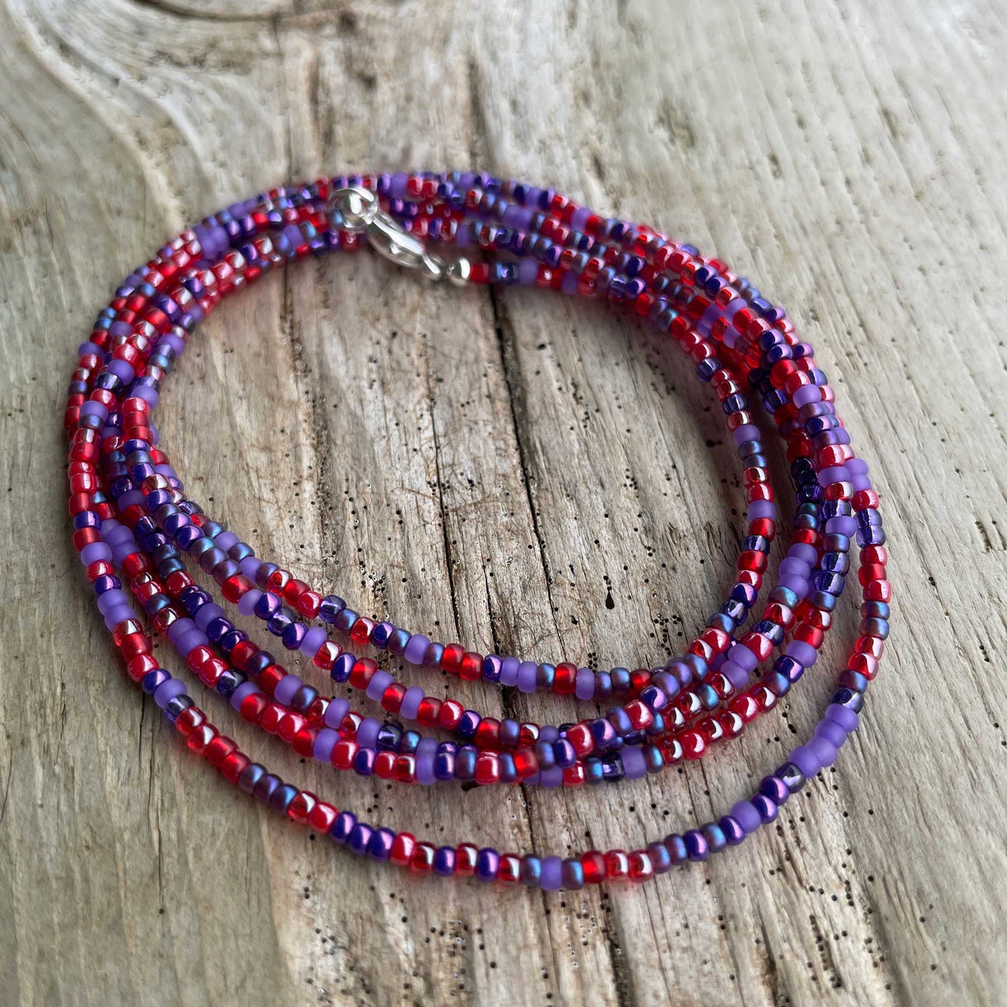 Beaded necklace with red and purple beads on a wooden surface