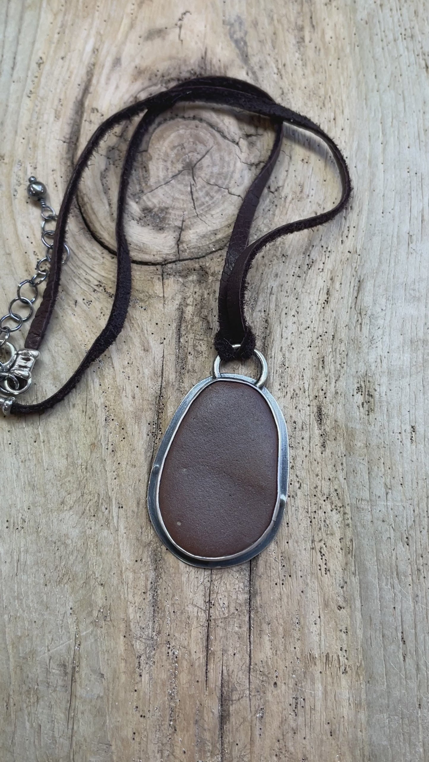 Load and play video in Gallery viewer, Brown Beach Stone Pendant in Sterling Silver with Deer Skin Lace
