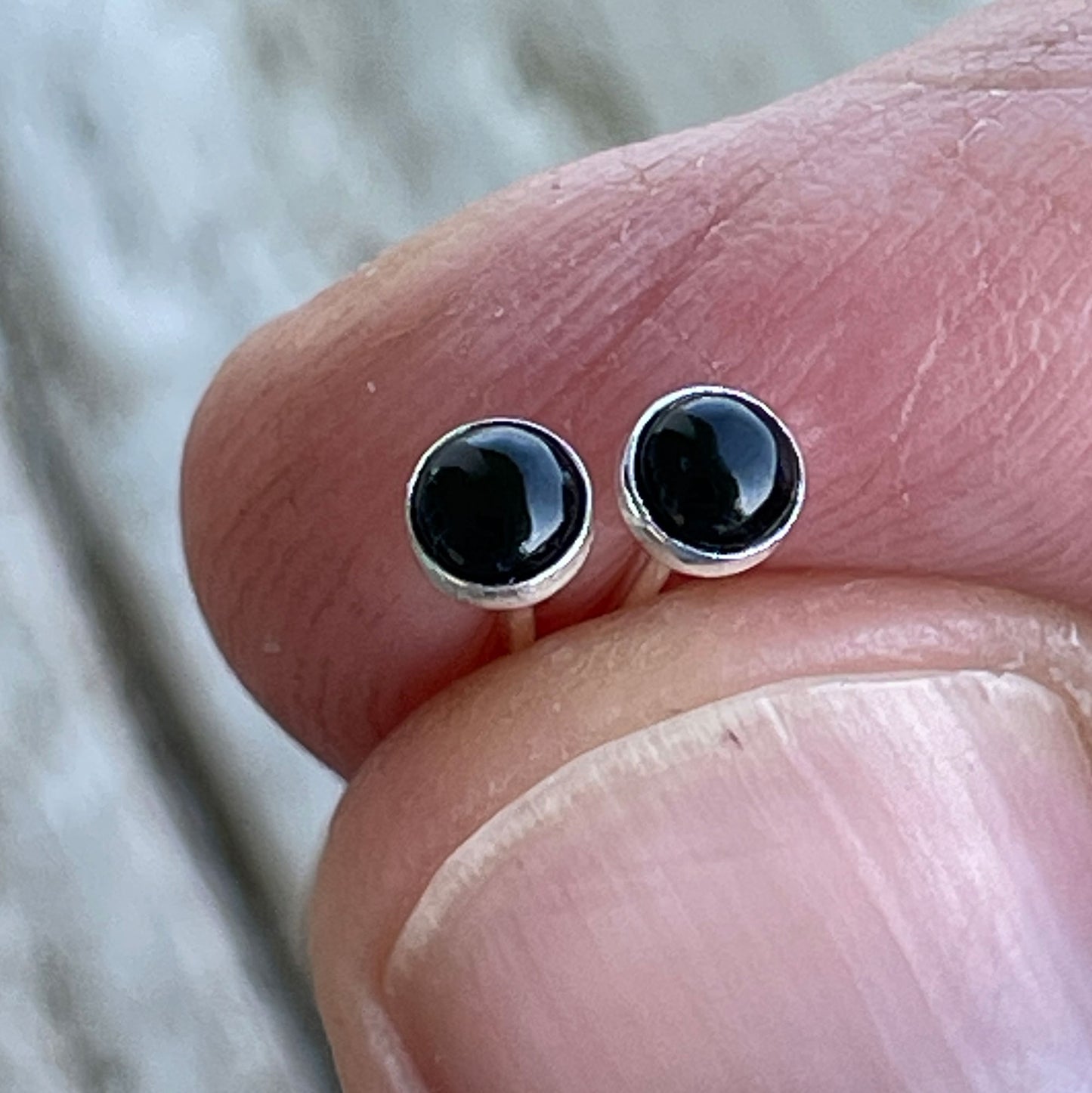Tiny 3mm Black onyx studs eld in finger tips to show how small they are