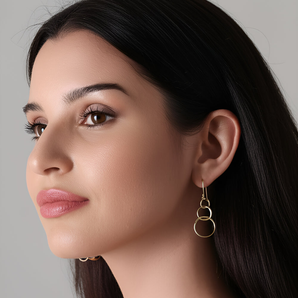 
                      
                        Woman wearing gold interlocking hoop earrings 
                      
                    