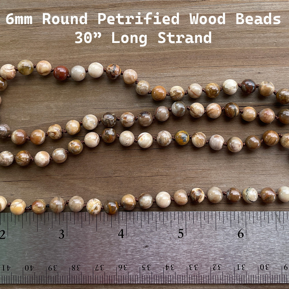 
                      
                        String of 6mm round petrified wood beads with a ruler for scale on a wooden surface
                      
                    