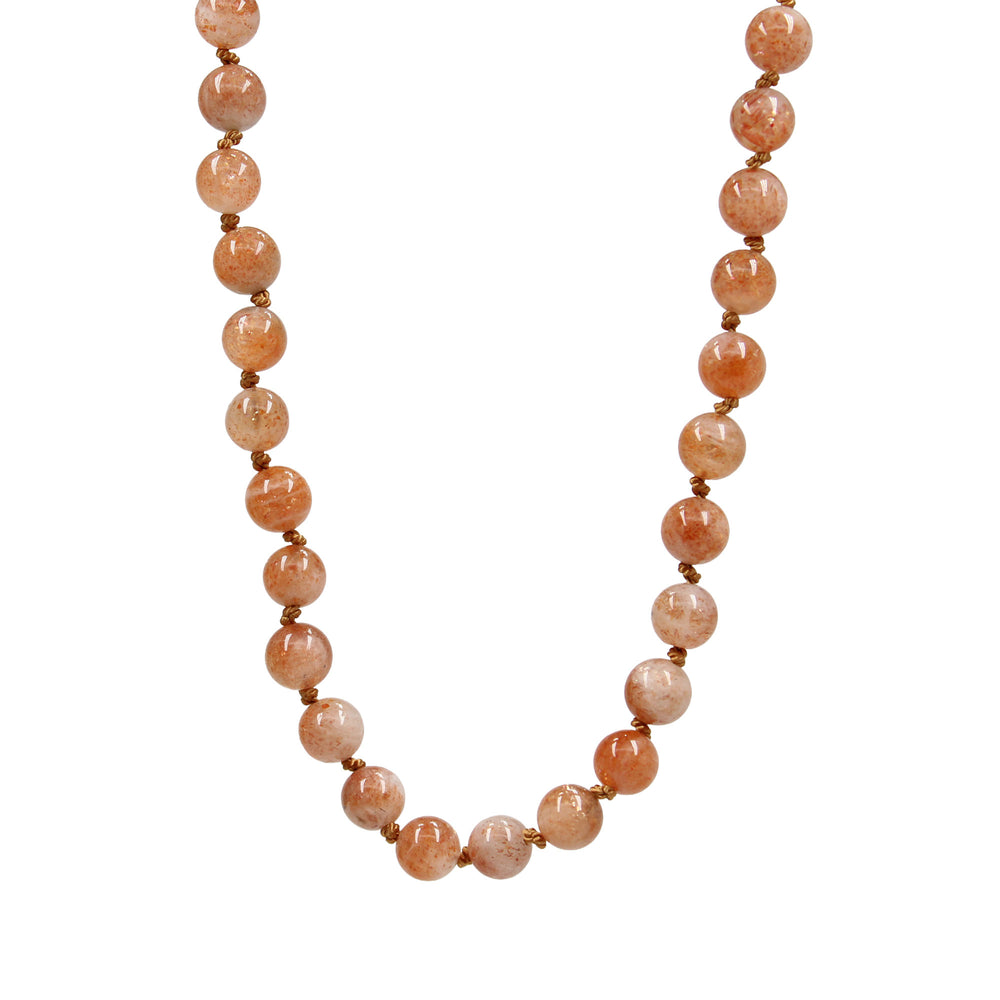 
                      
                        Necklace with peach-colored beads on a white background
                      
                    