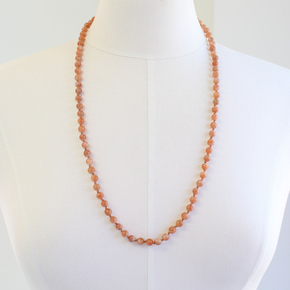 
                      
                        Necklace with small Sunstone beads on a mannequin against a white background
                      
                    