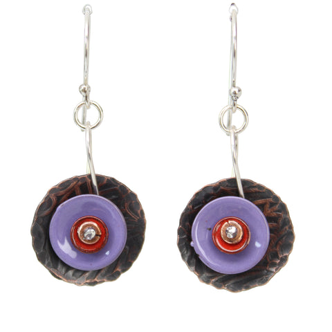 A pair of handmade dangle earrings featuring textured dark brown hammered copper discs, a central round purple enamel disc, a small red enamel accent, and a sterling silver fishhook ear wire 
