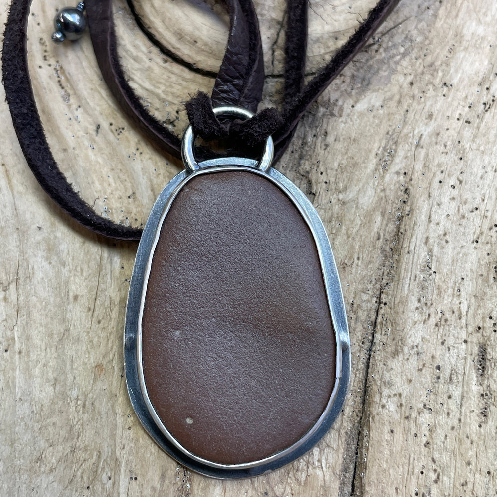 
                      
                        Handcrafted Brown Beach Stone Pendant in Sterling Silver with Deer Skin Lace
                      
                    